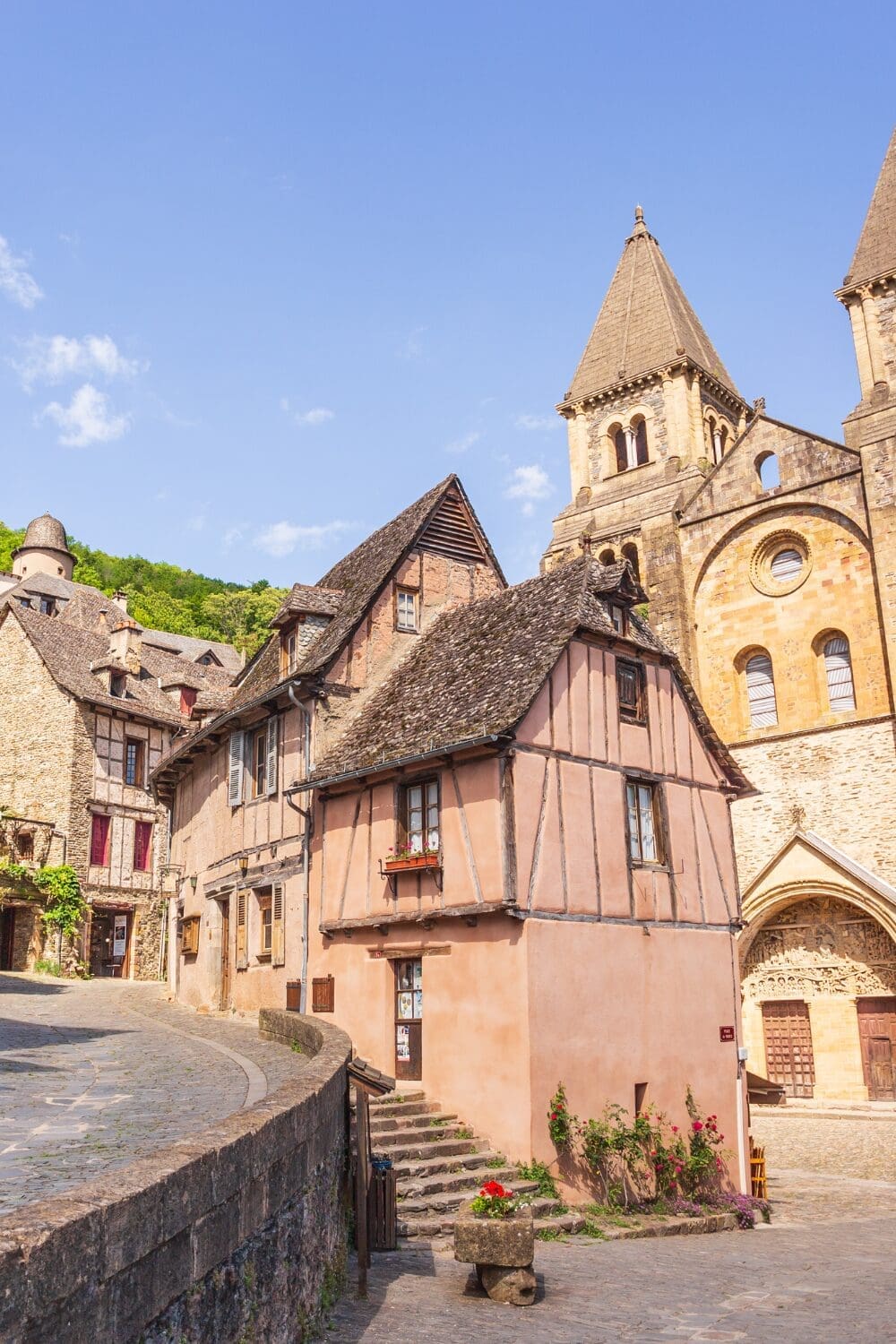 Medieval pink stone building and Romanesque abbey tower in Conques Aveyron secret French village