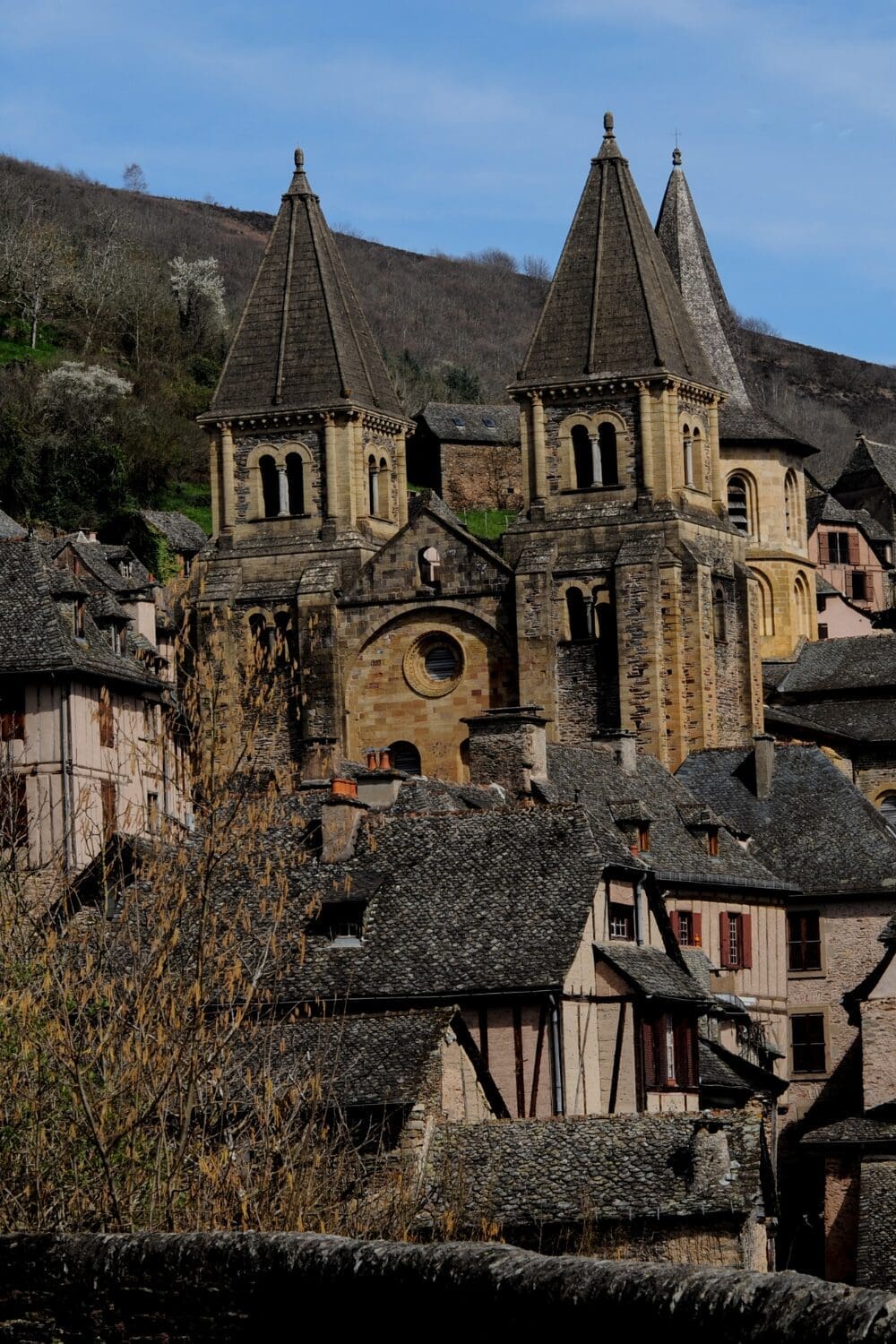 Romanesque abbey twin towers rising above medieval stone rooftops in Conques Aveyron France