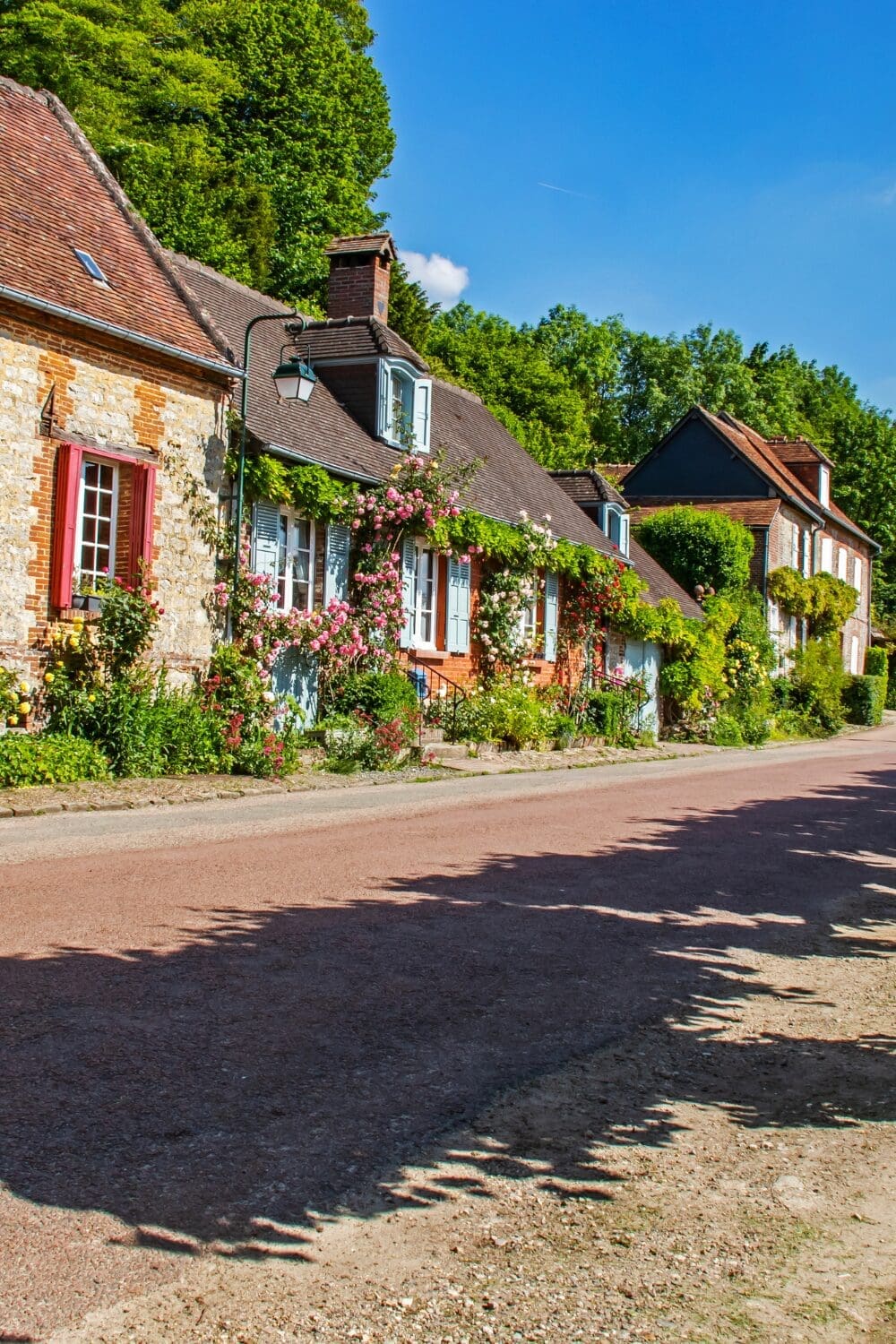 Rose covered stone cottages on cobblestone street Gerberoy Picardy secret French village
