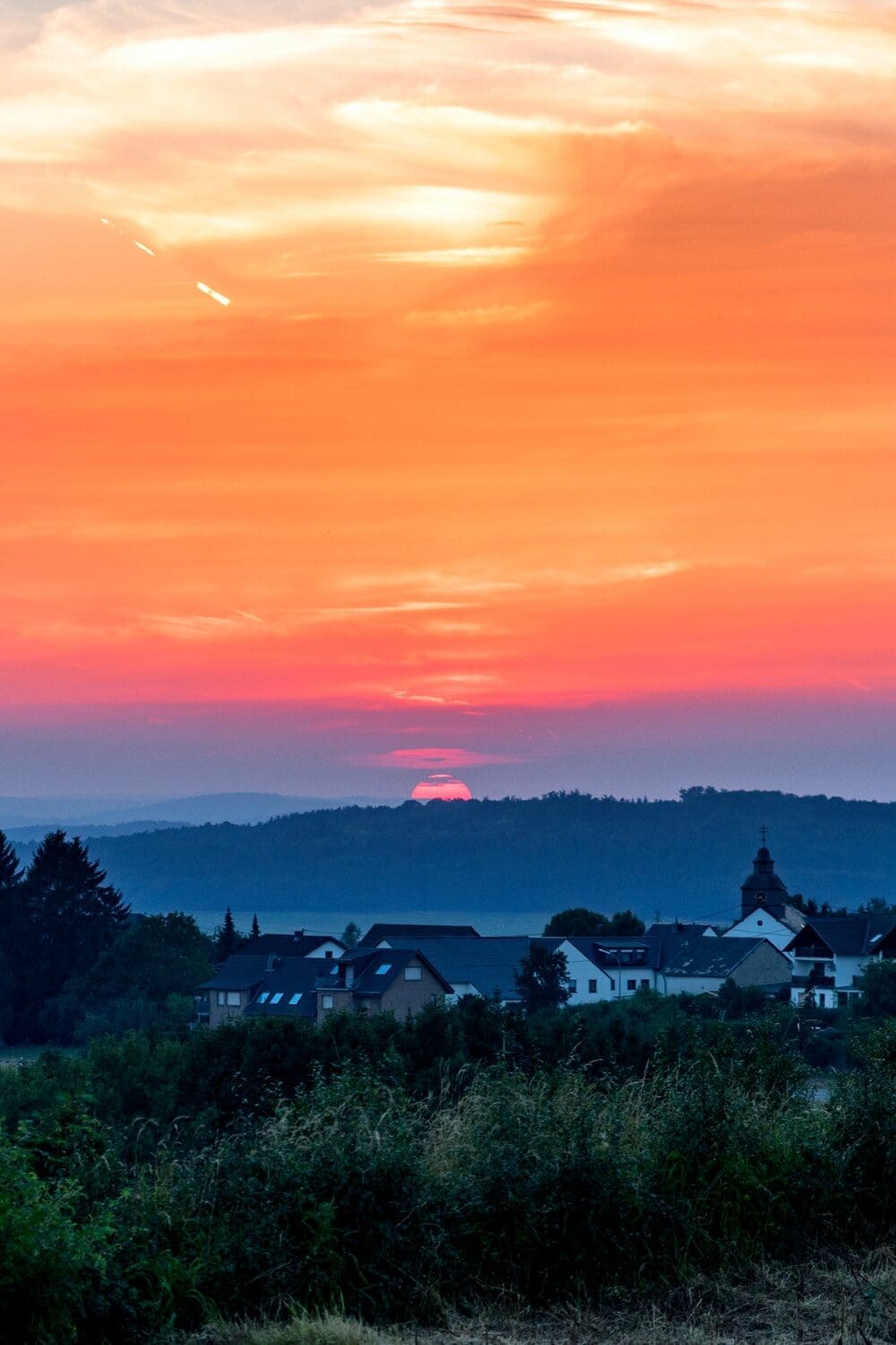 Blazing coral and orange sunset over quiet French village with church steeple silhouette, Loire Valley France before the crowds