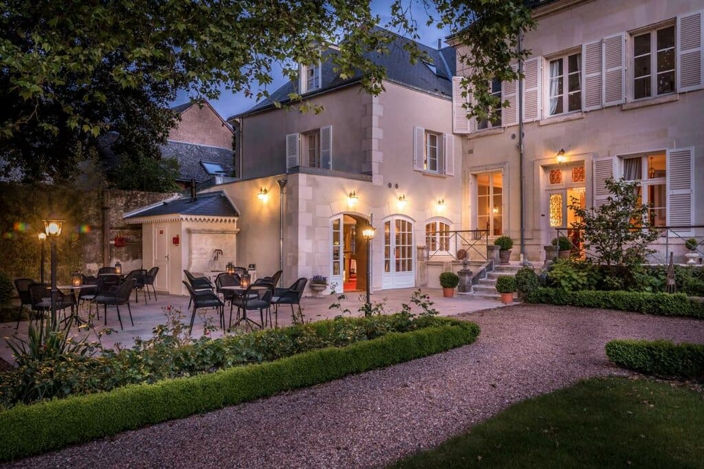 Luxury boutique hotel garden patio at night with lanterns and manicured hedges France