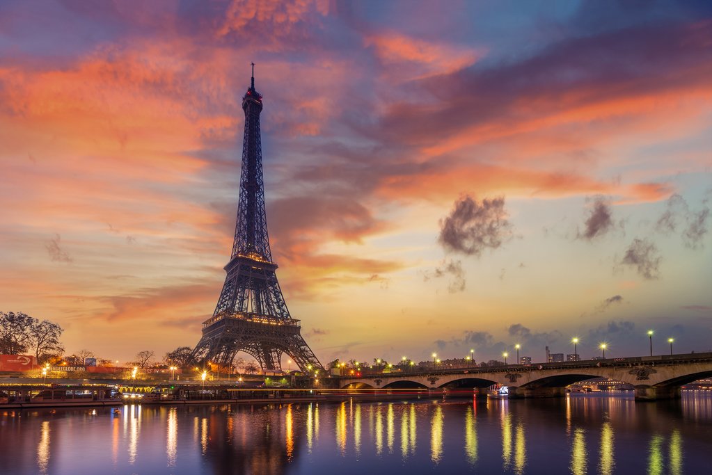 Sunrise over the Eiffel Tower and the Seine River, glowing orange sky for a Paris in May packing guide