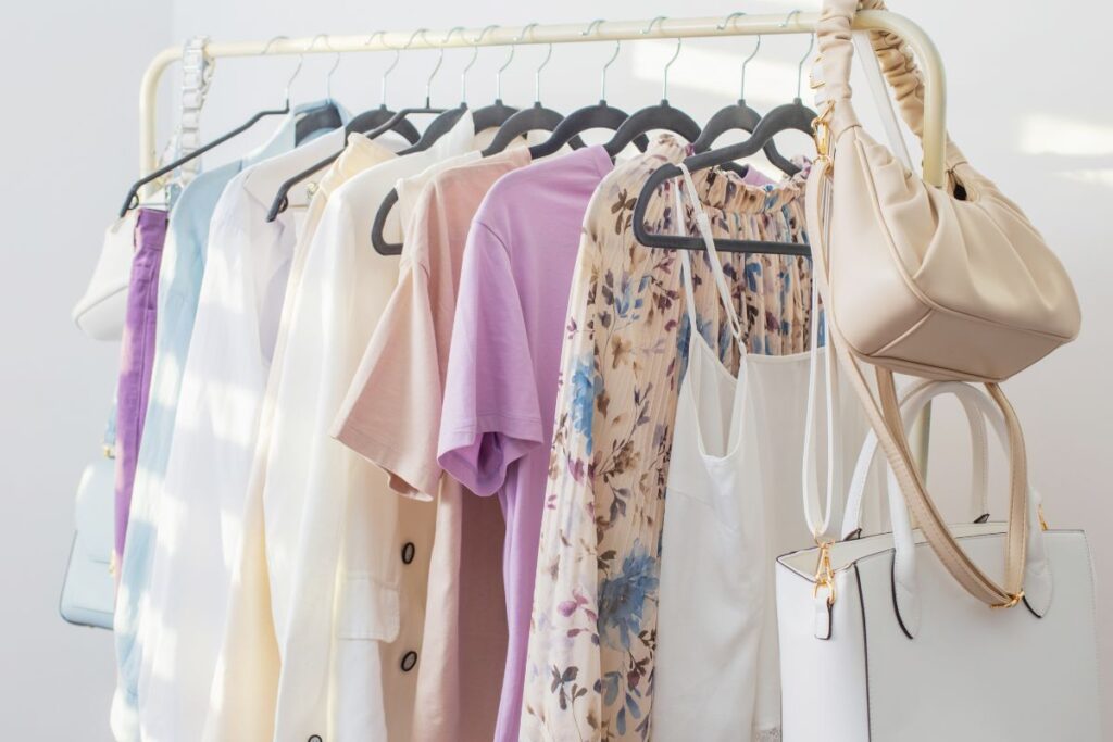 Neutral and pastel capsule wardrobe hanging on a clothing rack for a Paris in May packing guide